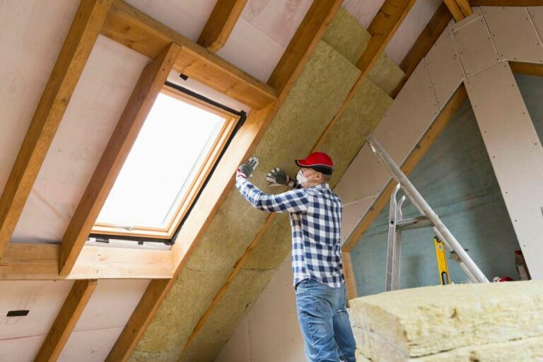 Man installing thermal roof insulation layer using mineral wool panels. Attic renovation and insulation concept